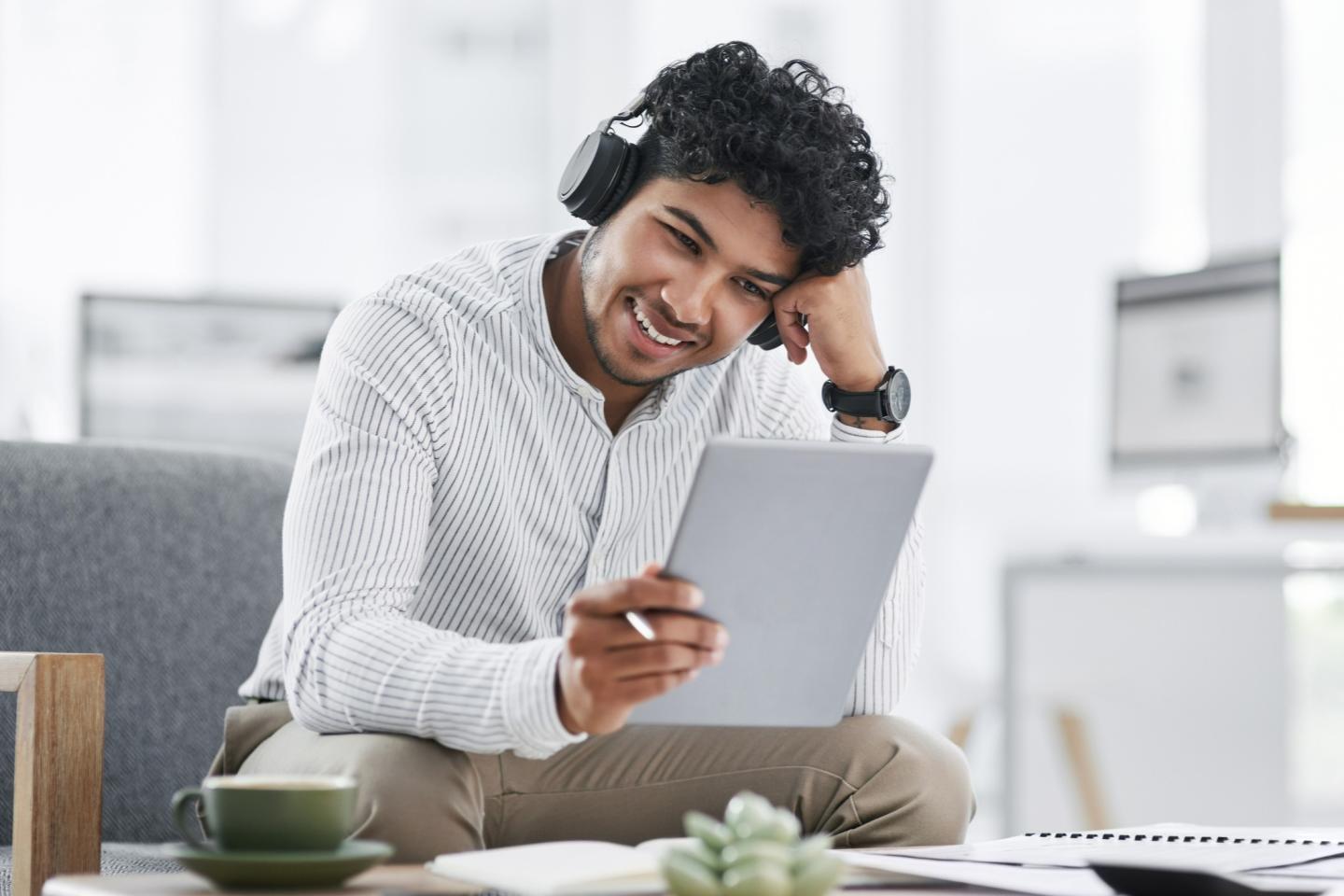 Un homme qui porte des ecouteurs et regarde une tablette