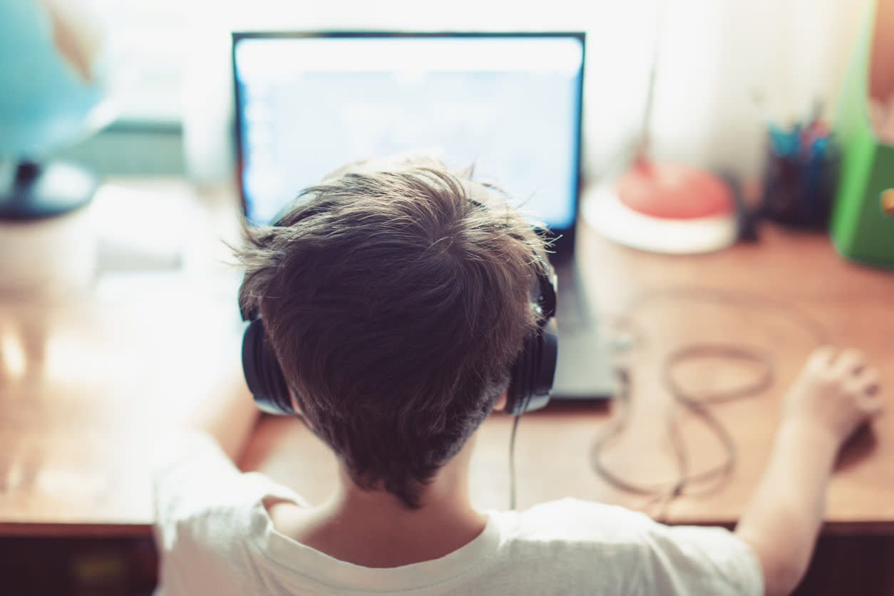 Child playing games on a laptop, wearing headphones