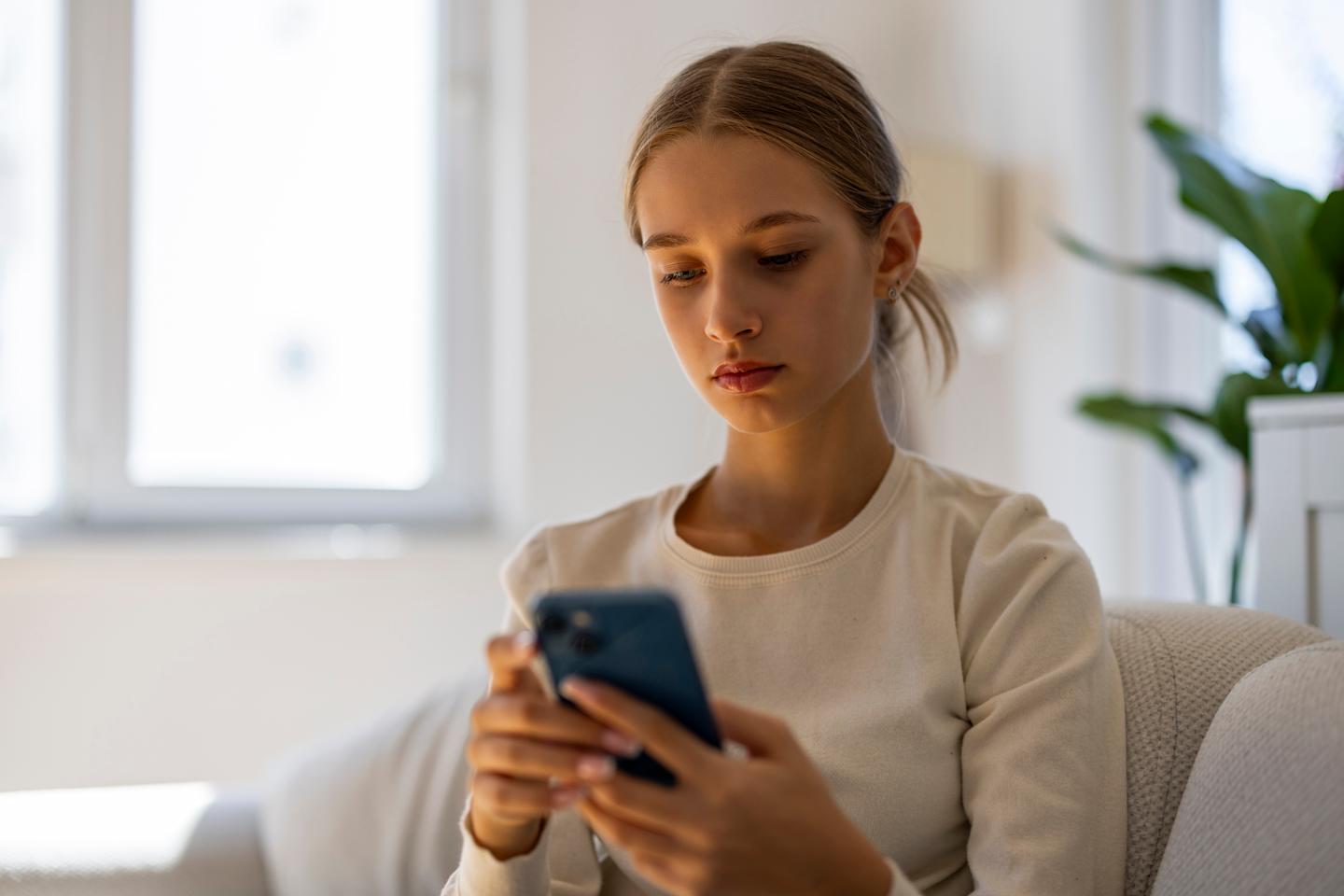 A stressed teenager looking at their phone. 