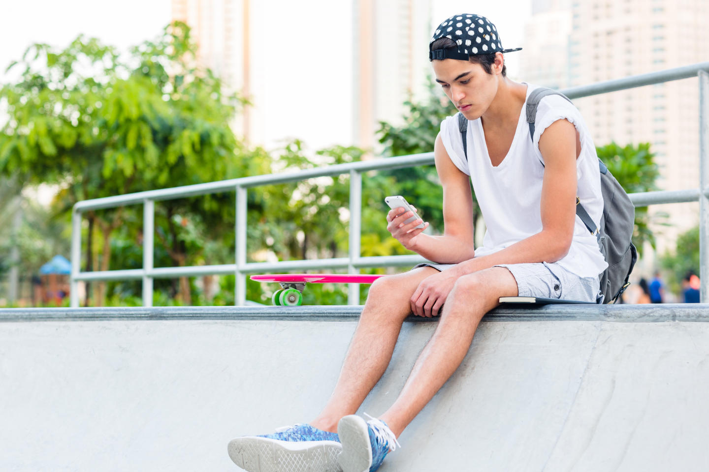 Teen boy texting at a skate park