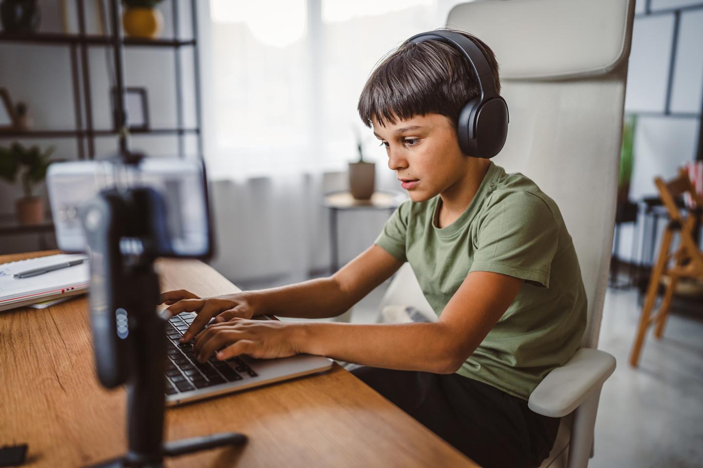An image showing a child using a laptop with headphones.