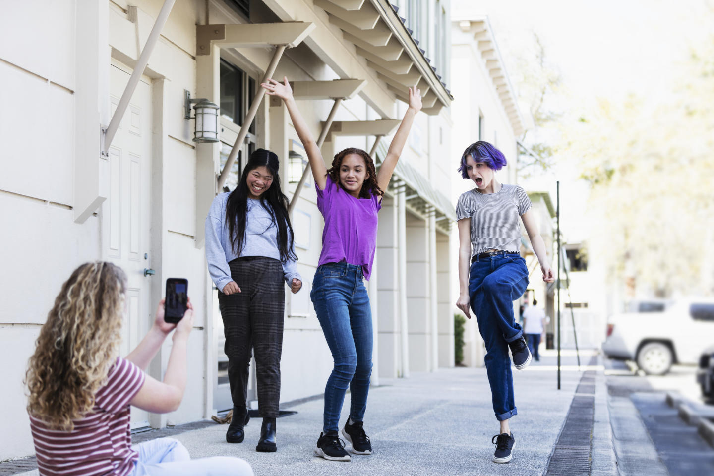 Teens filming on smartphone outdoors.