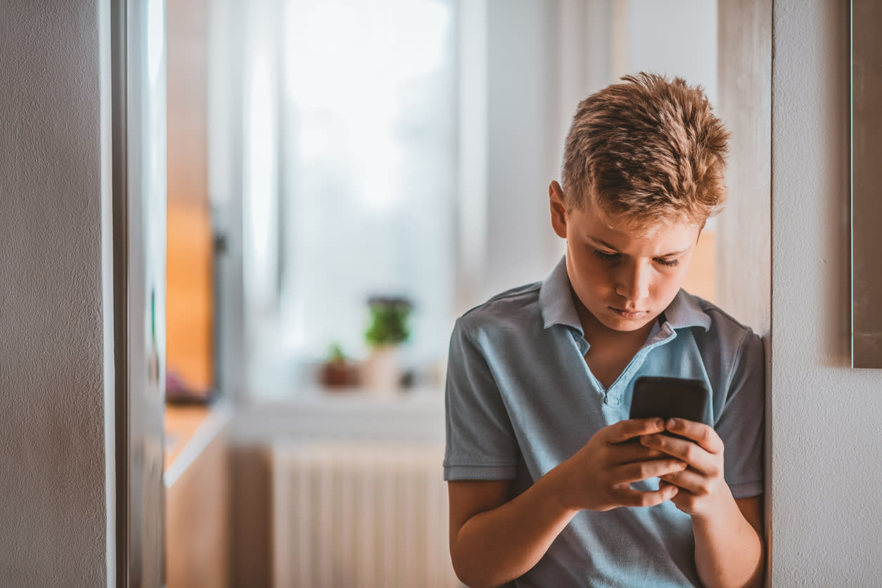 Child using mobile device with a worried look on his face. 