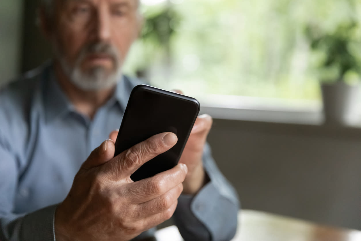 An older man looks at his smartphone