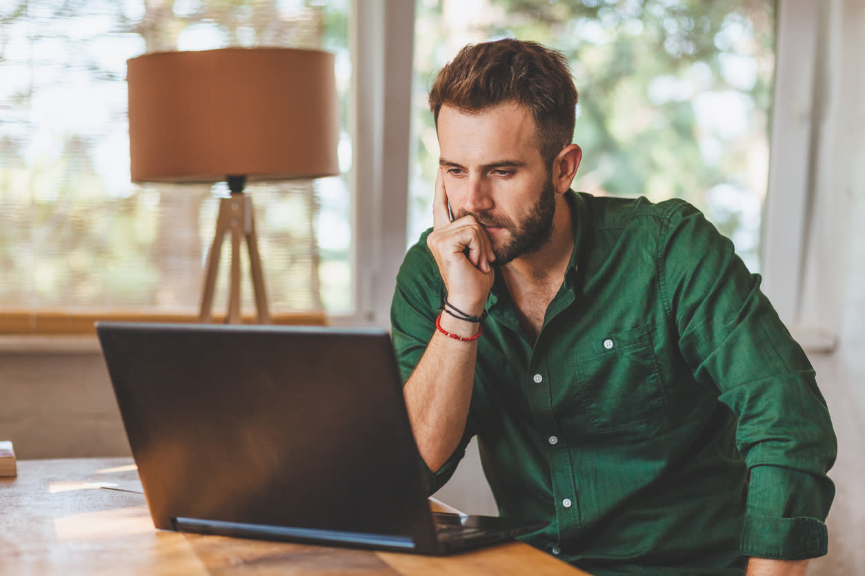 A man in a green shirt looks intently at his laptop