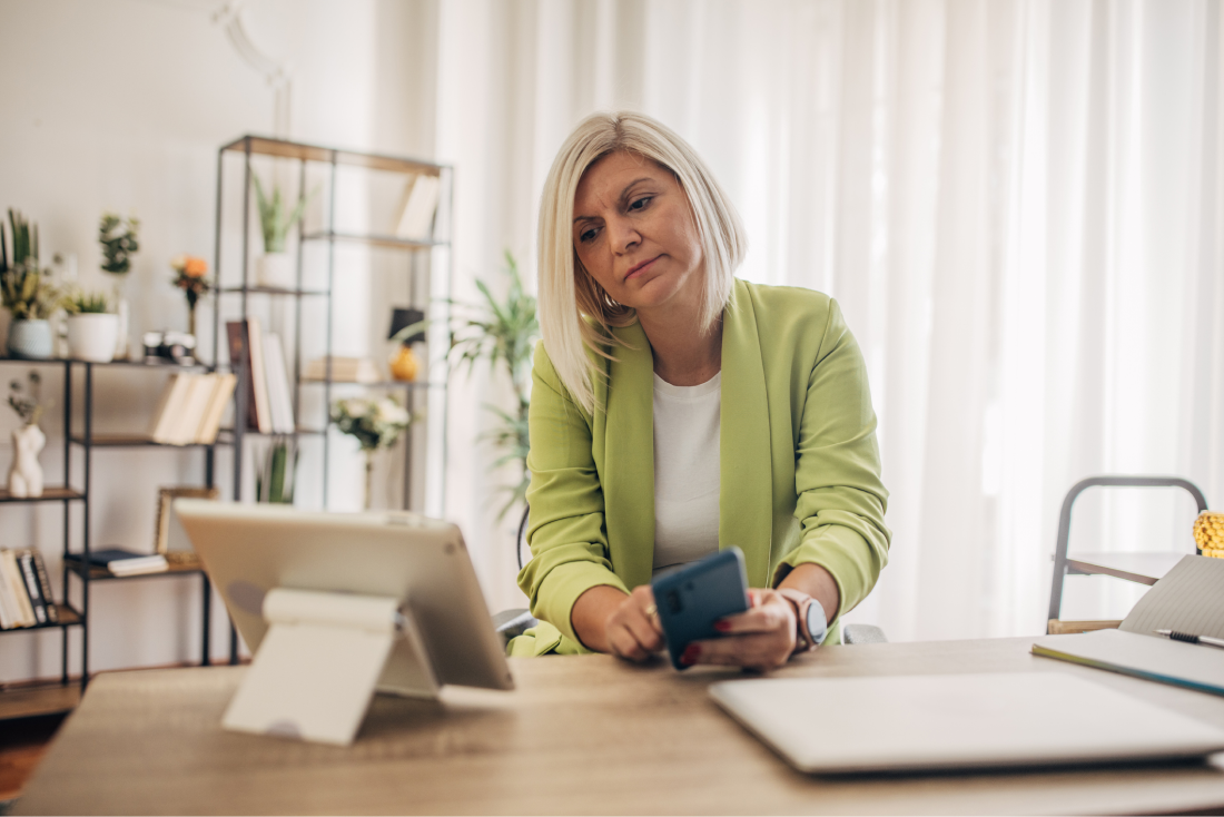 Woman in their home office using smartphone and tablet. 