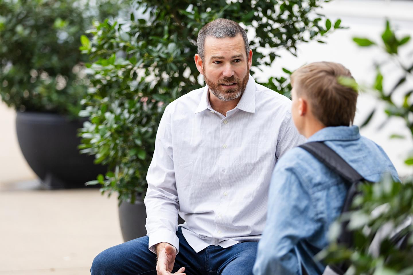 A parent talking to their teenager outside.