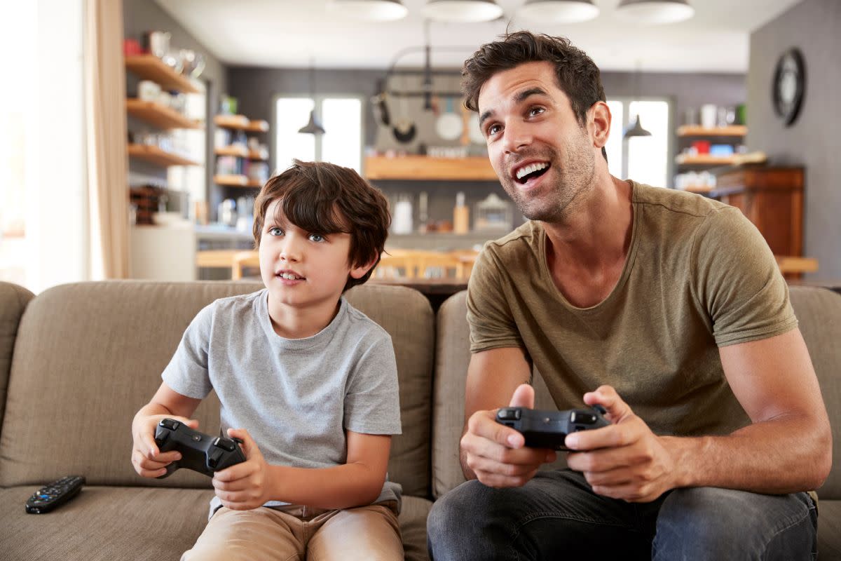 Father and son sitting on a sofa playing video games.