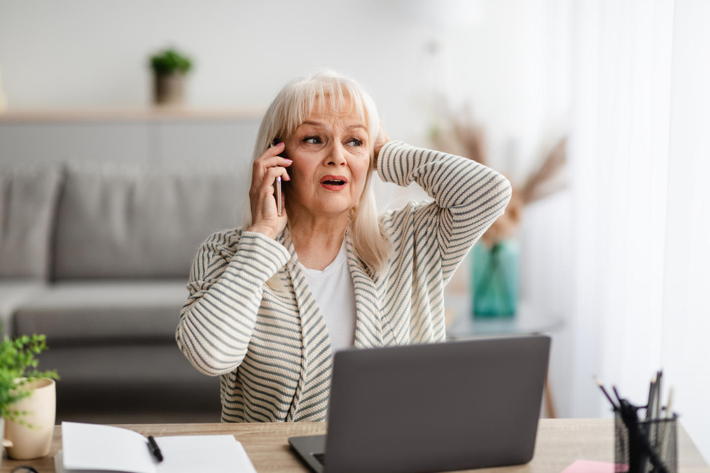 Shocked senior woman talking on mobile phone