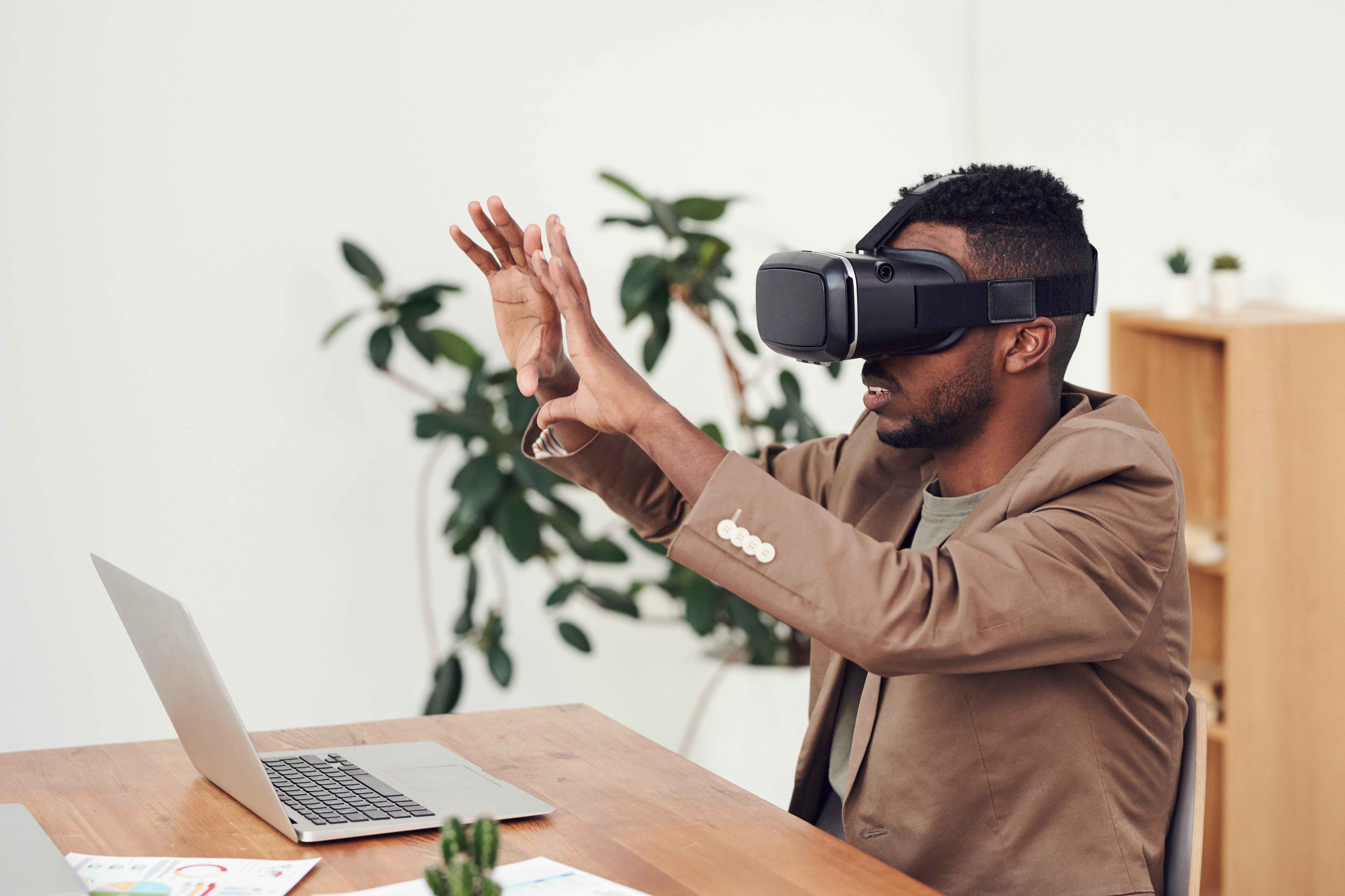 man wearing virtual reality glasses while working on a laptop.