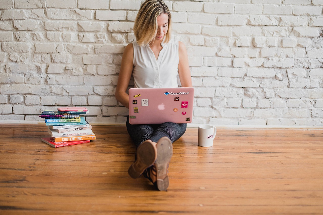 woman sitting on a wooden bench with a laptop.