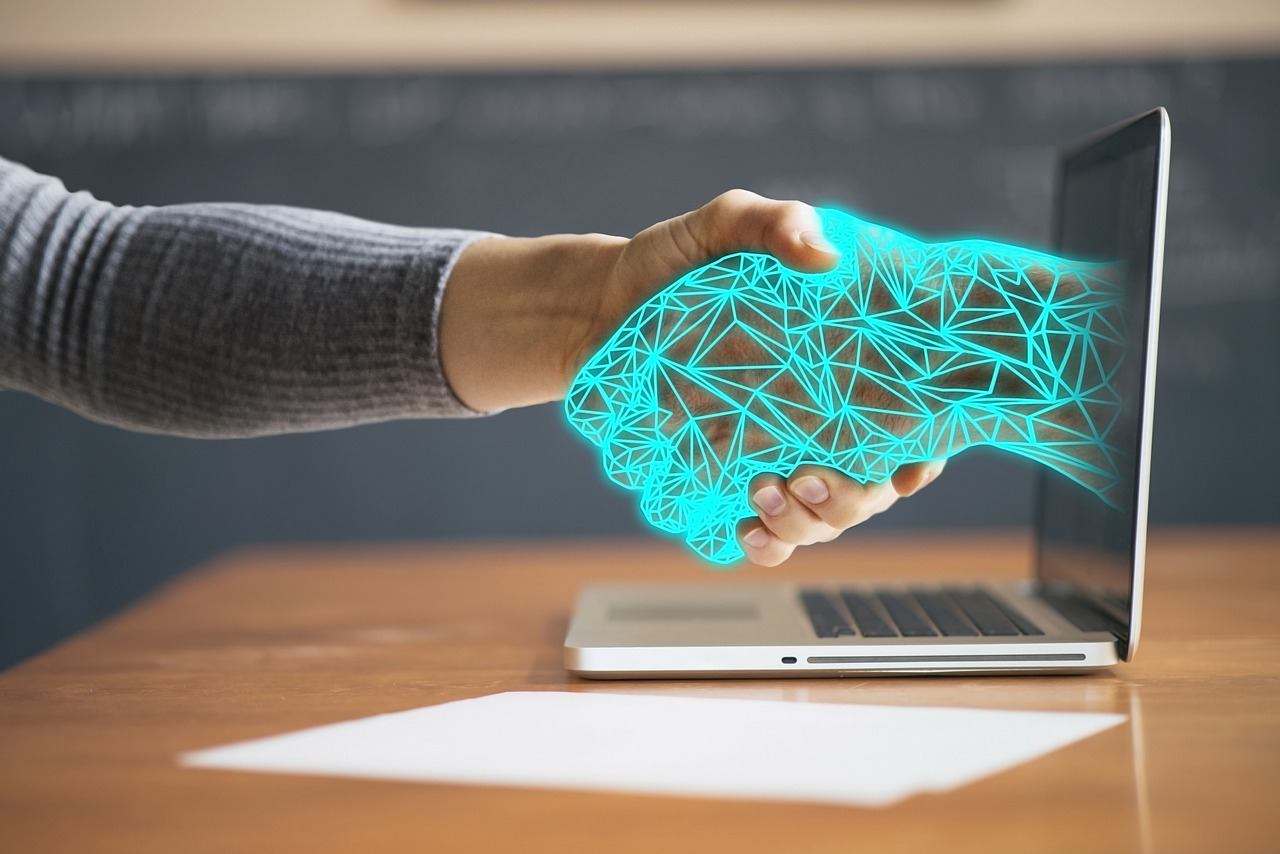 a woman's hand holding a laptop with a glowing screen.