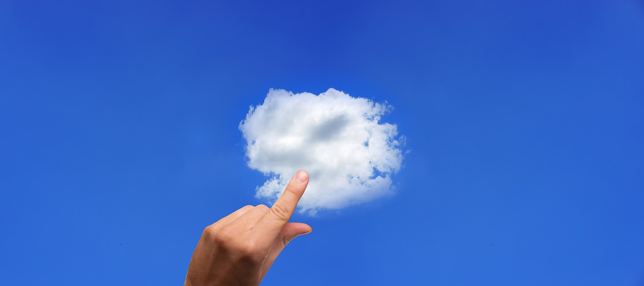 hand holding a cloud with blue sky background.