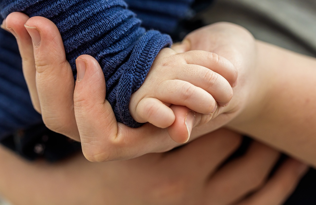 a baby's hand holding a baby's foot.