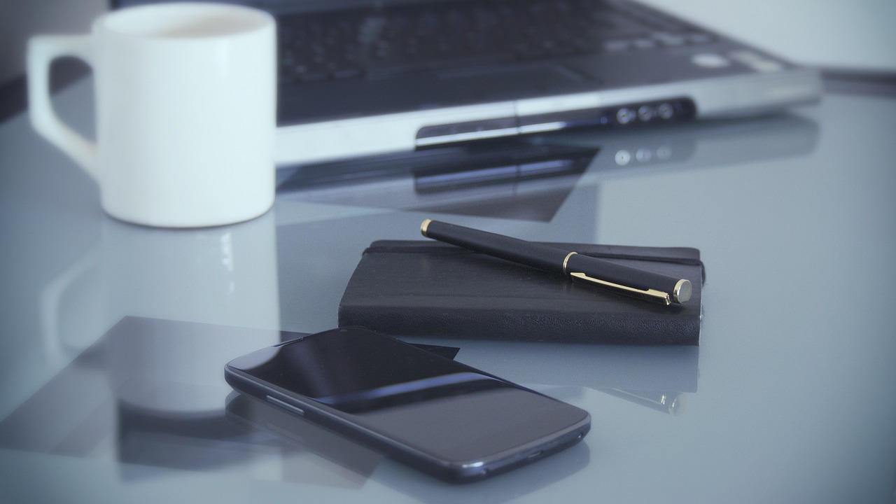 a black pen and a black smartphone on a desk.