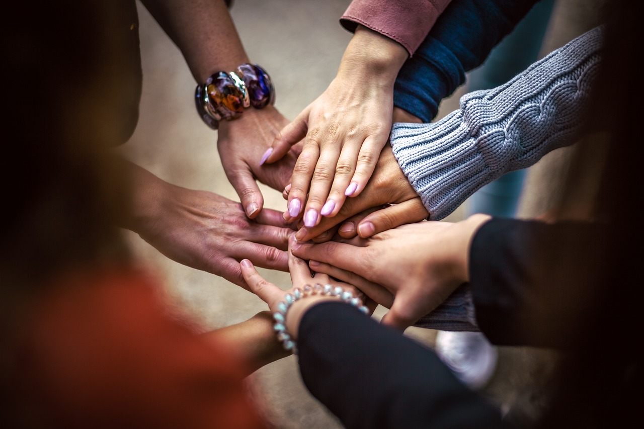 hands of multiracial friends holding each other.