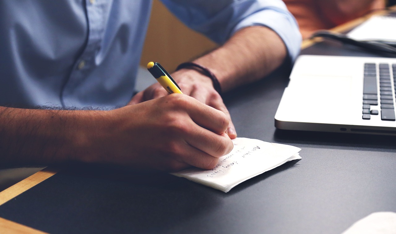 man writing on a notebook.