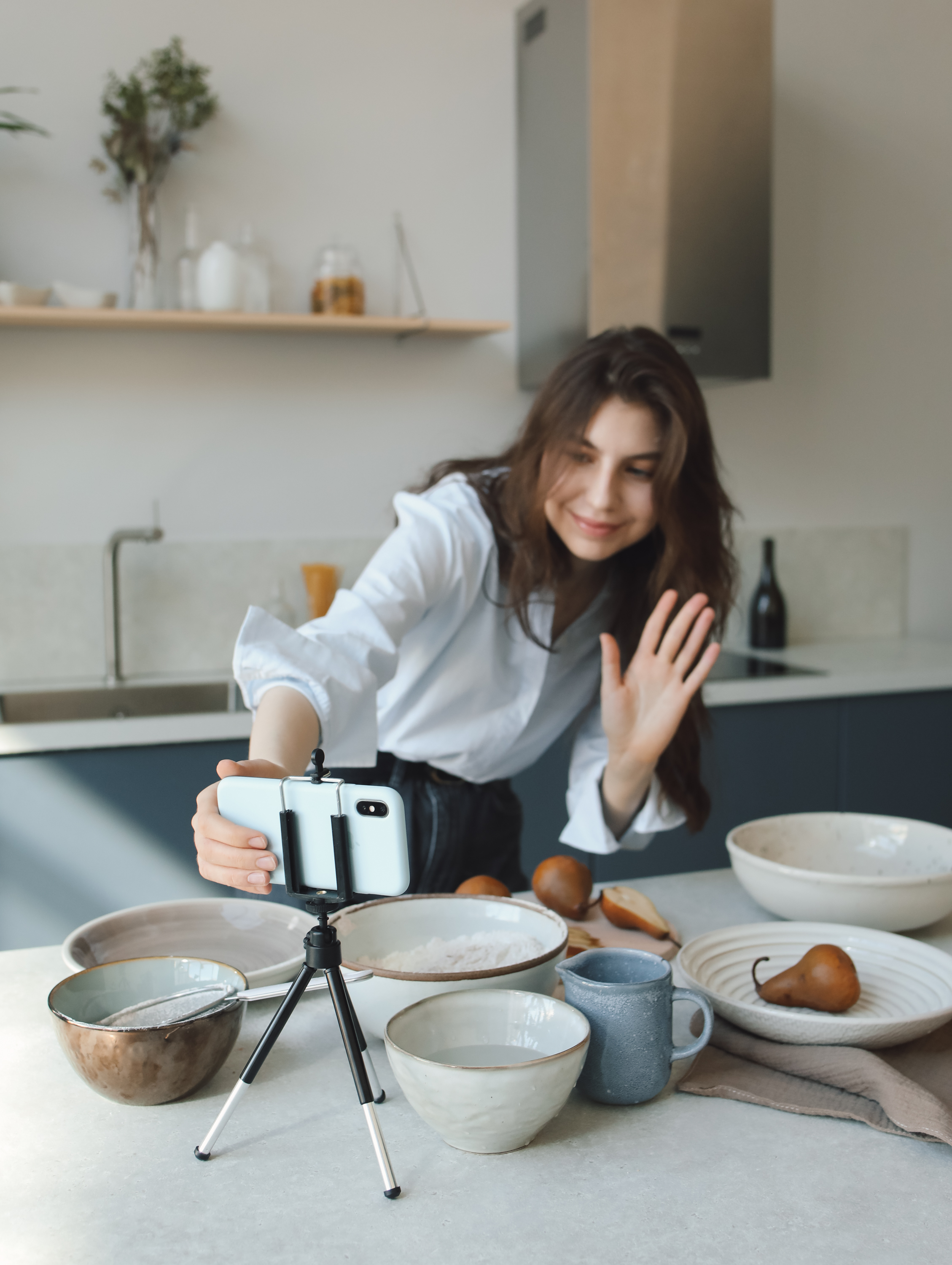 young woman in apron with a camera taking pictures of food.