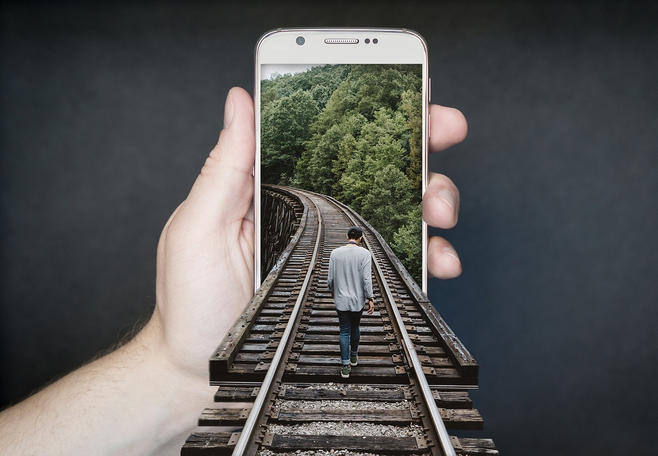 man holding a smartphone with a train in the background.