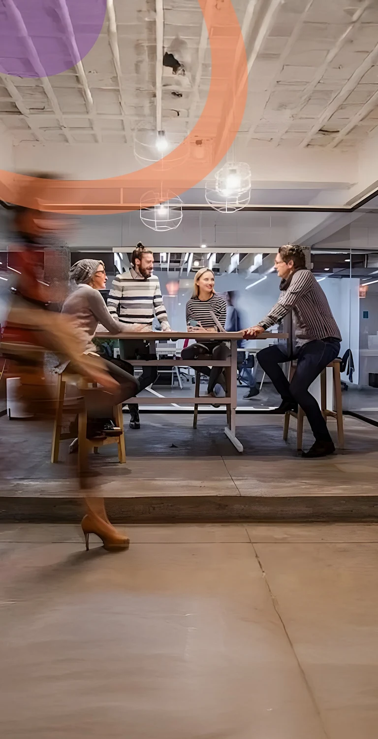 Pessoas caminhando em ambiente empresarial, pessoas sentadas numa mesa ao fundo