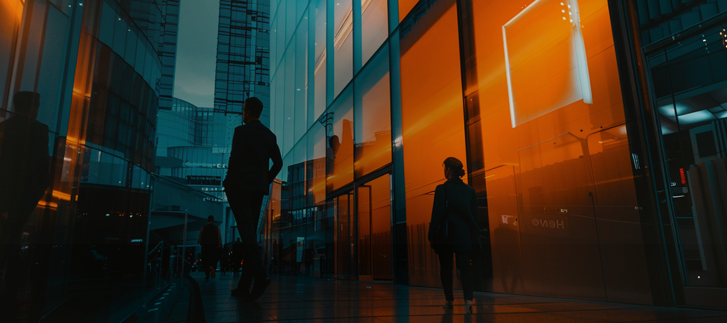 Imagem de um prédio moderno com fachadas de vidro refletindo o pôr do sol, com três pessoas caminhando na frente, ideal para arquitetura moderna.