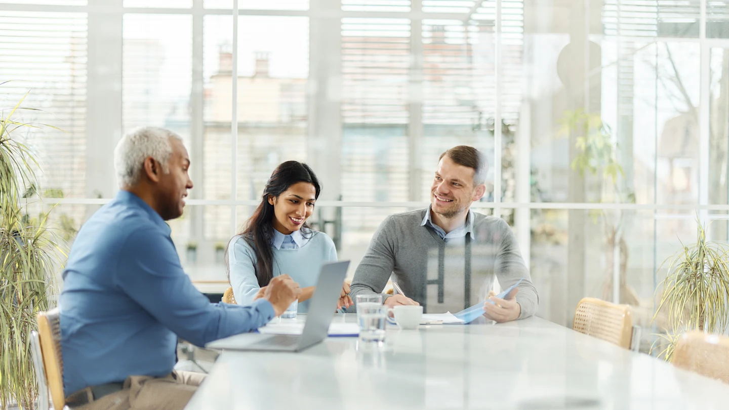 Pessoas sentadas em uma mesa de trabalho conversando