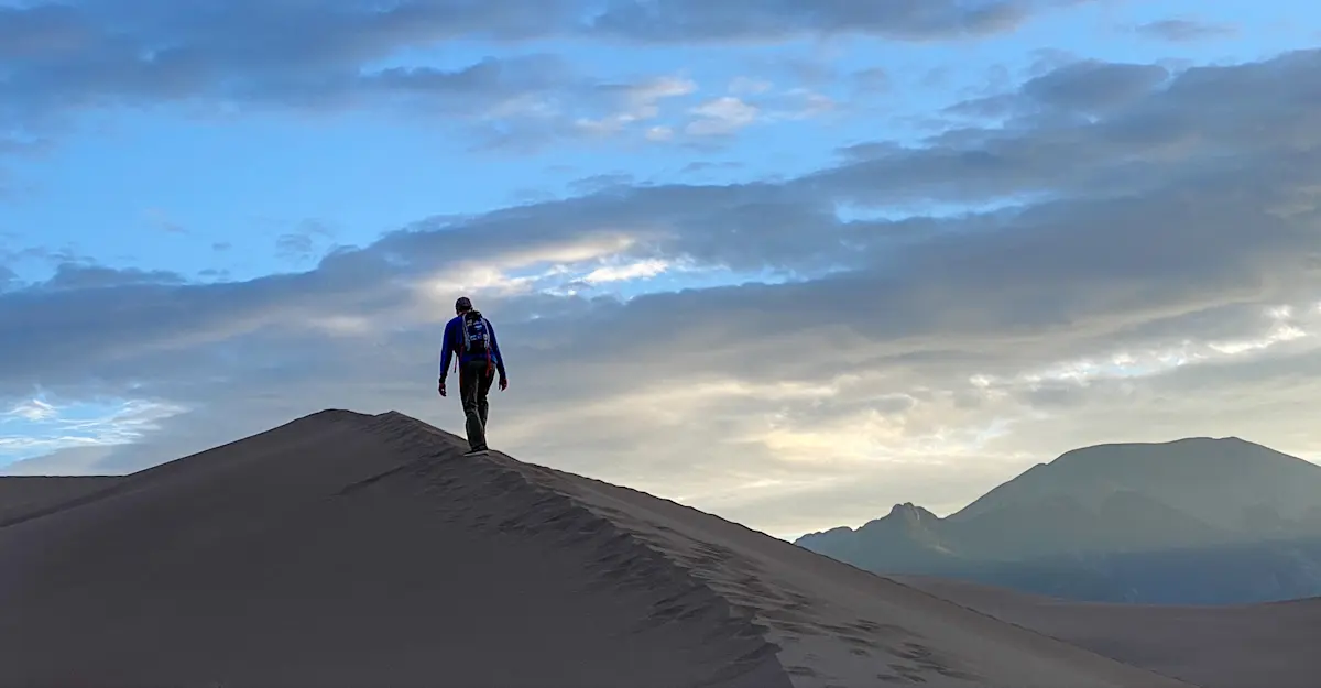 Climbing the highest dune in Great Sand Dunes National Park & Preserve at sunrise.