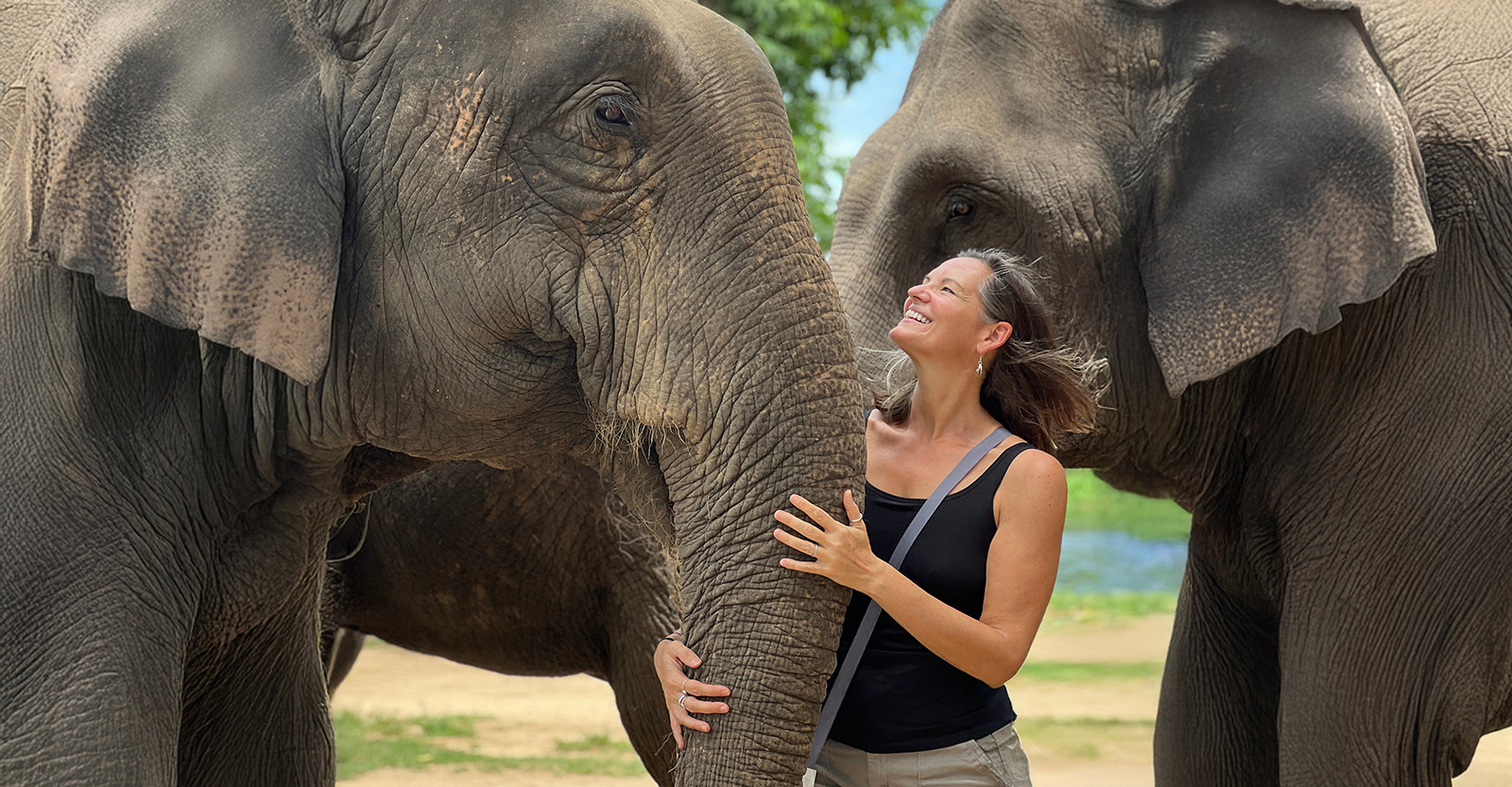 Smiling alongside gentle giants at an elephant sanctuary in Kanchanaburi, Thailand.