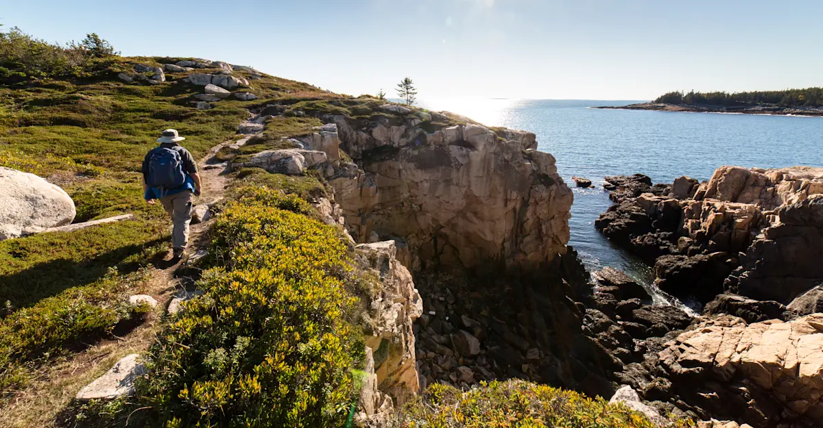 Earthwatch Expeditions guest hiking along the coastline, Acadia National Park, Maine.