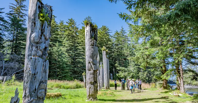 Nat Hab guests and totem poles, Gwaii Haanas National Park Reserve, British Columbia.