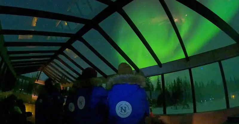Travelers viewing northern lights from inside Nat Hab's Aurora Pod®