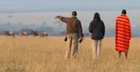 Nat Hab guests, Maasai and wildebeest, Private Mara Conservancy, Kenya.