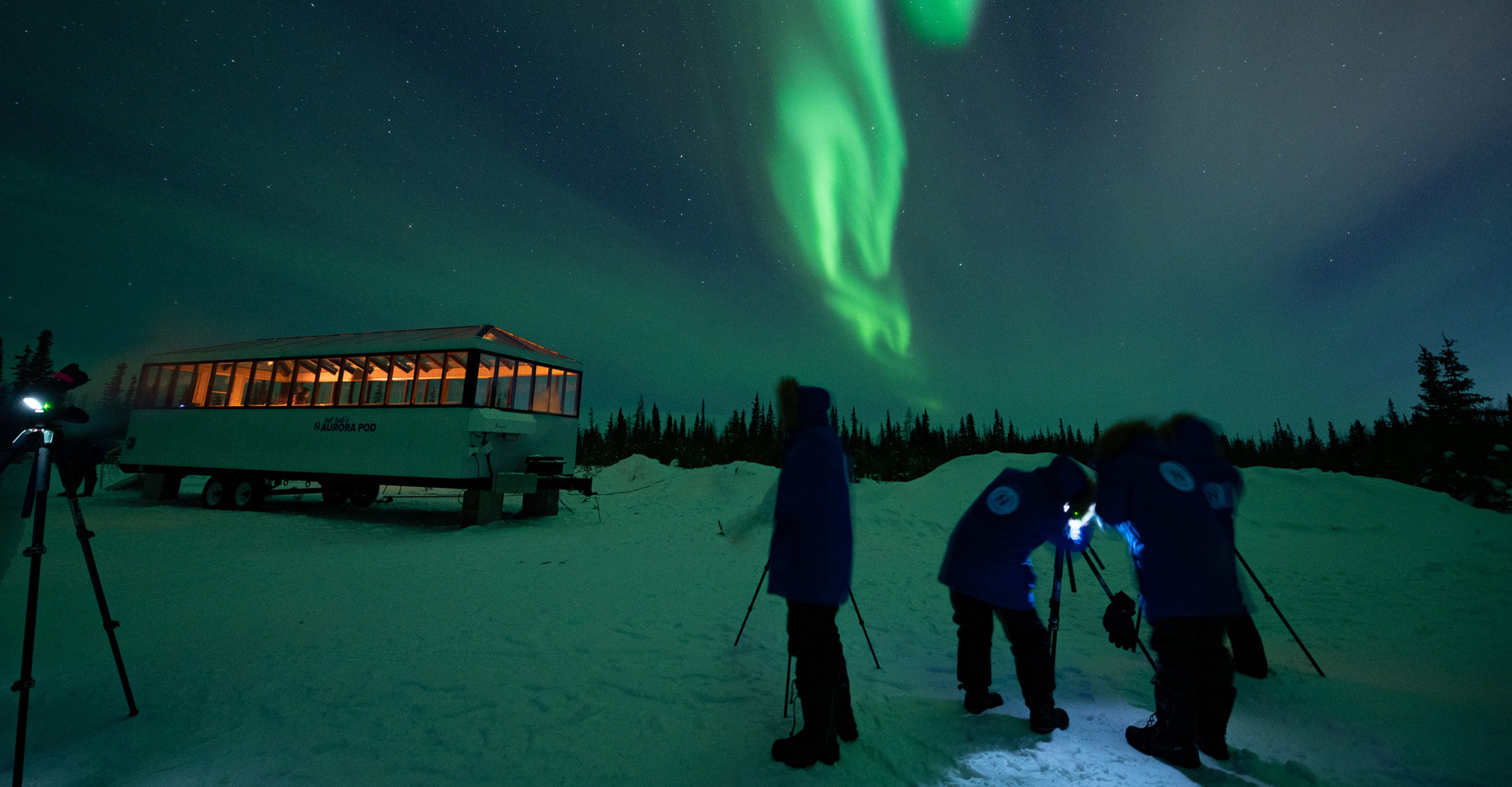 Travelers taking photos of northern lights outside of Nat Hab's Aurora Pod®