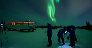 Travelers taking photos of northern lights outside of Nat Hab's Aurora Pod®