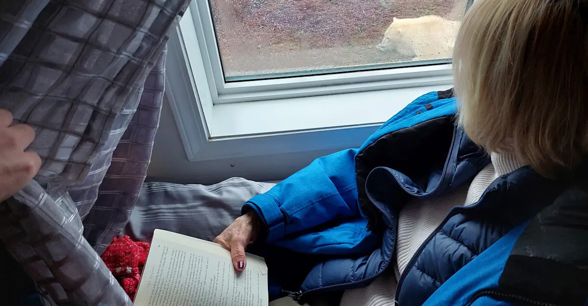 Traveler viewing polar bears from bed in Nat Hab's Tundra Lodge