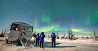 Travelers viewing northern lights outside Nat Hab's Aurora Pod® 