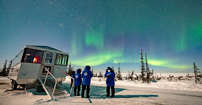 Travelers viewing northern lights outside Nat Hab's Aurora Pod® 