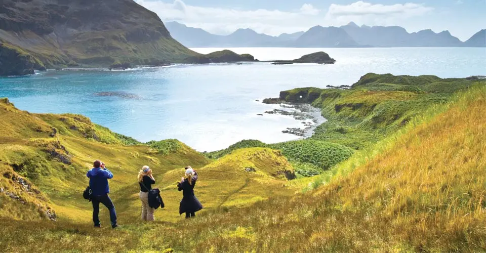 Travelers hiking up hillside, South Georgia Island.