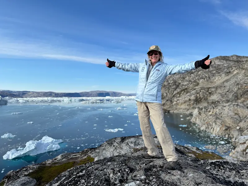 On a cliffside, soaking in surreal views I’ll never forget near Tasiilaq, Greenland.