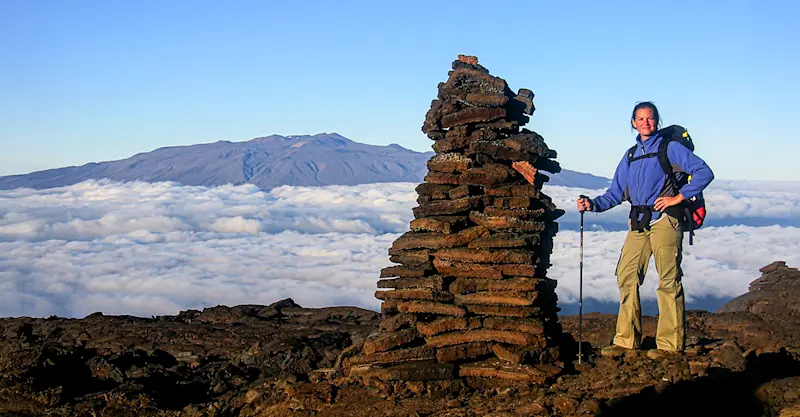 Hiking across volcanic landscapes with Mauna Kea on the horizon in Hawaii.