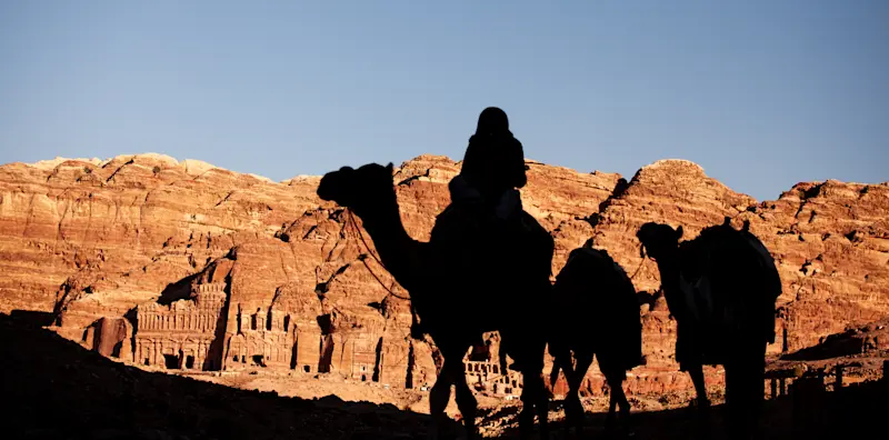 Camel back riding through the vast desert land of Petra, Jordan.