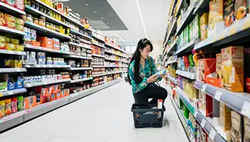 A women shopping in an aisle at a convenience store.