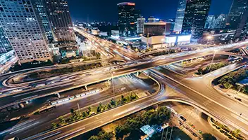 bright lights of cityscape at night with blurred cars driving on freeway.