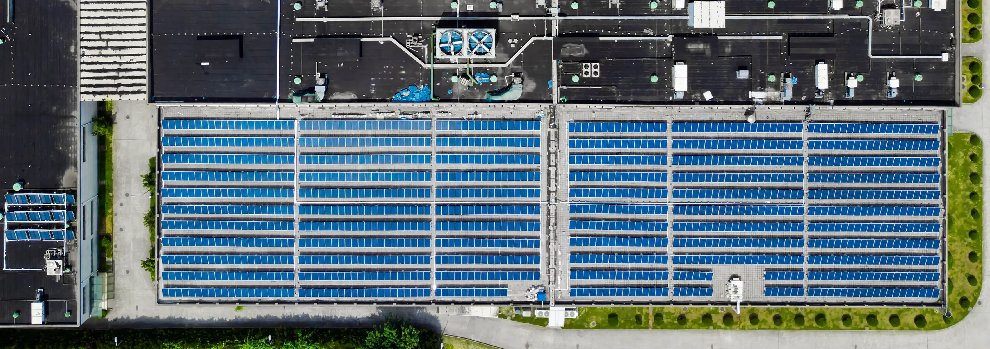An aerial view of a large industrial facility with extensive rooftop solar panels