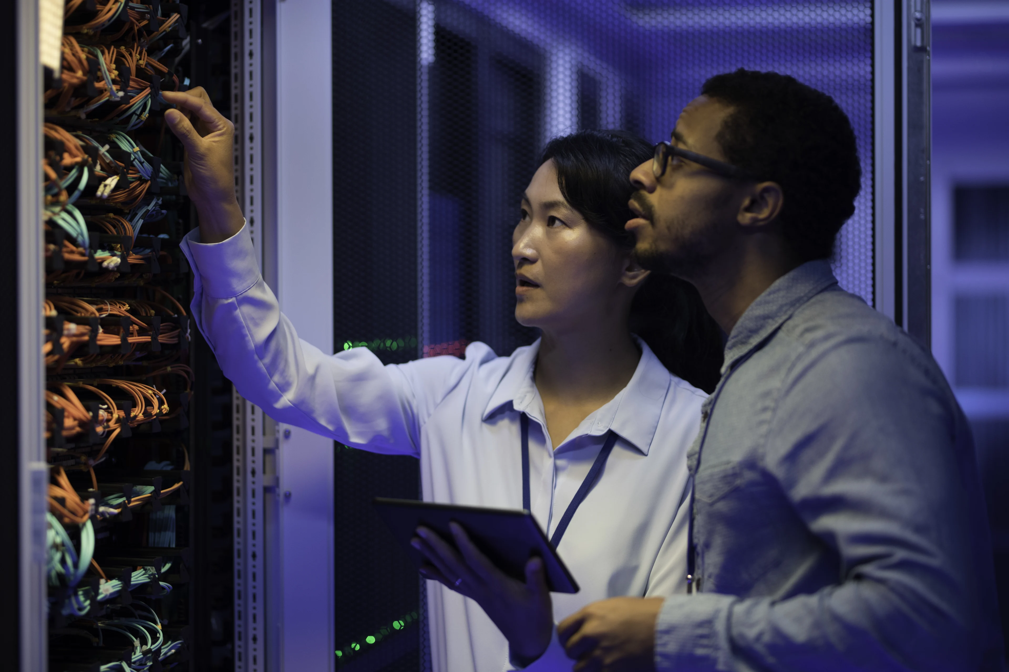 IT engineers examining server connections in a data center.