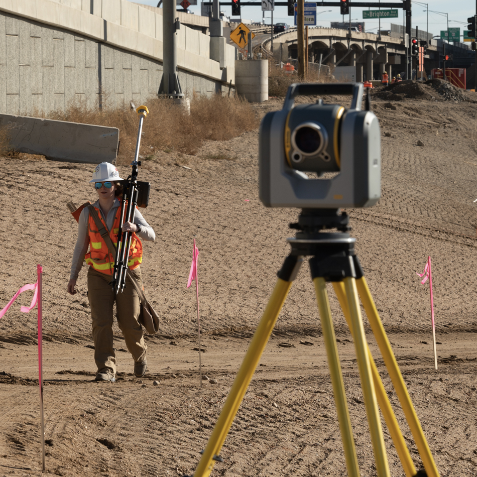 Surveyor walking to a Trimble SX12 total station at construction site