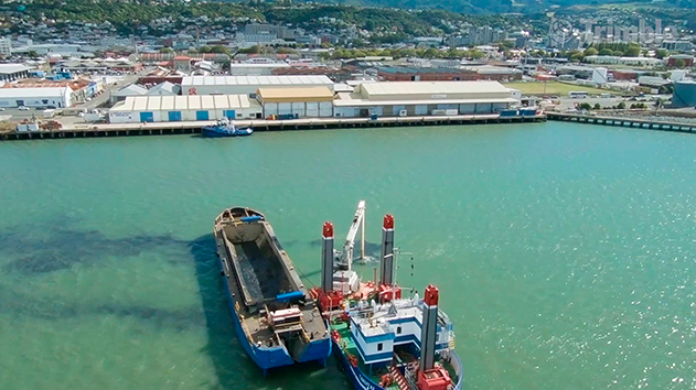 A dredge vessel and a barge in an urban port working on a marine construction project