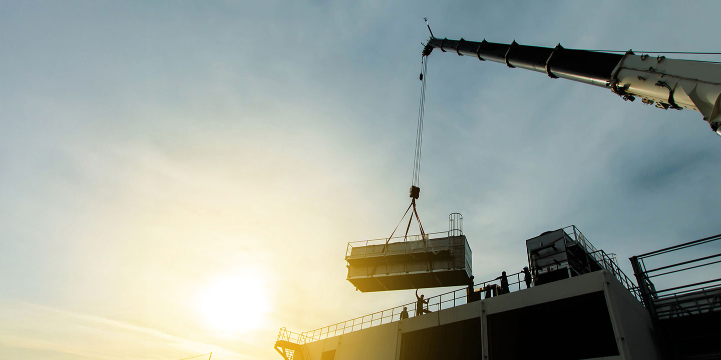 A crane lifting a large mechanical unit onto a roof