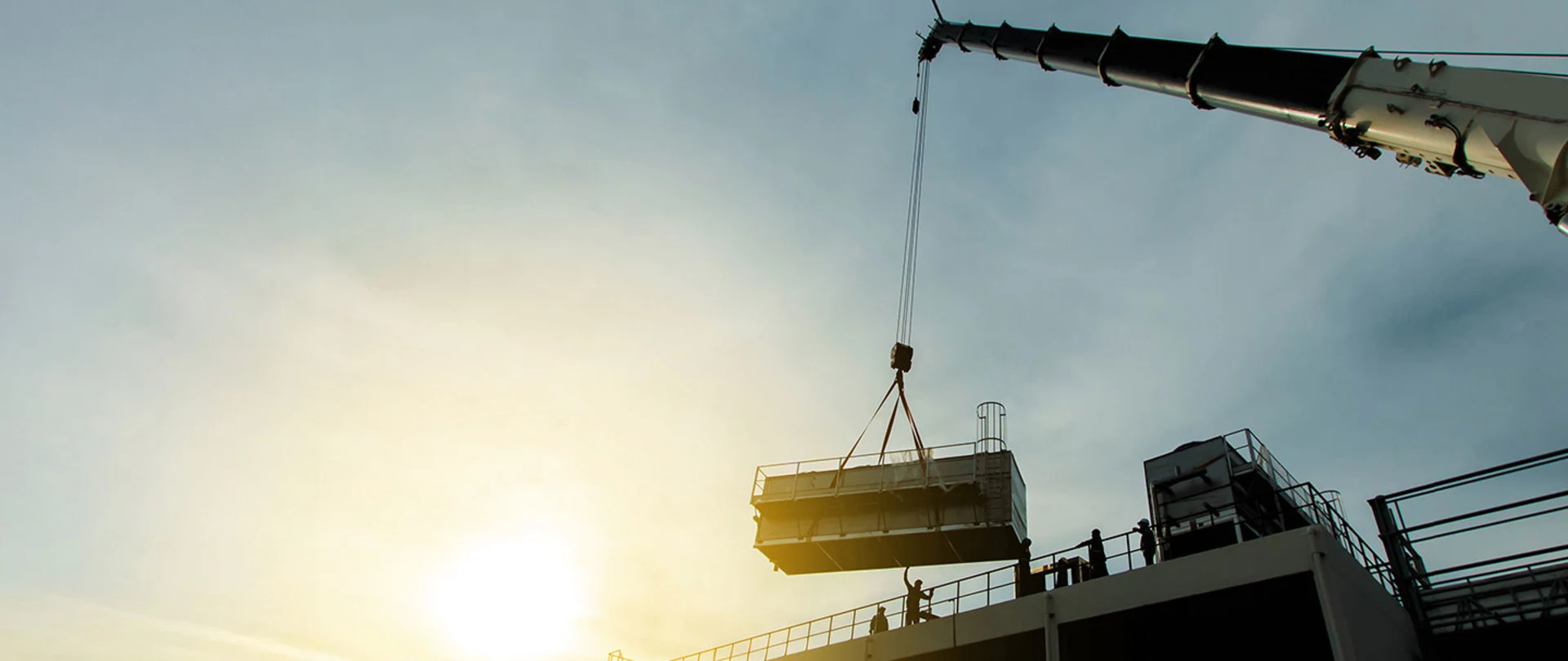 A crane lifting a large mechanical unit onto a roof