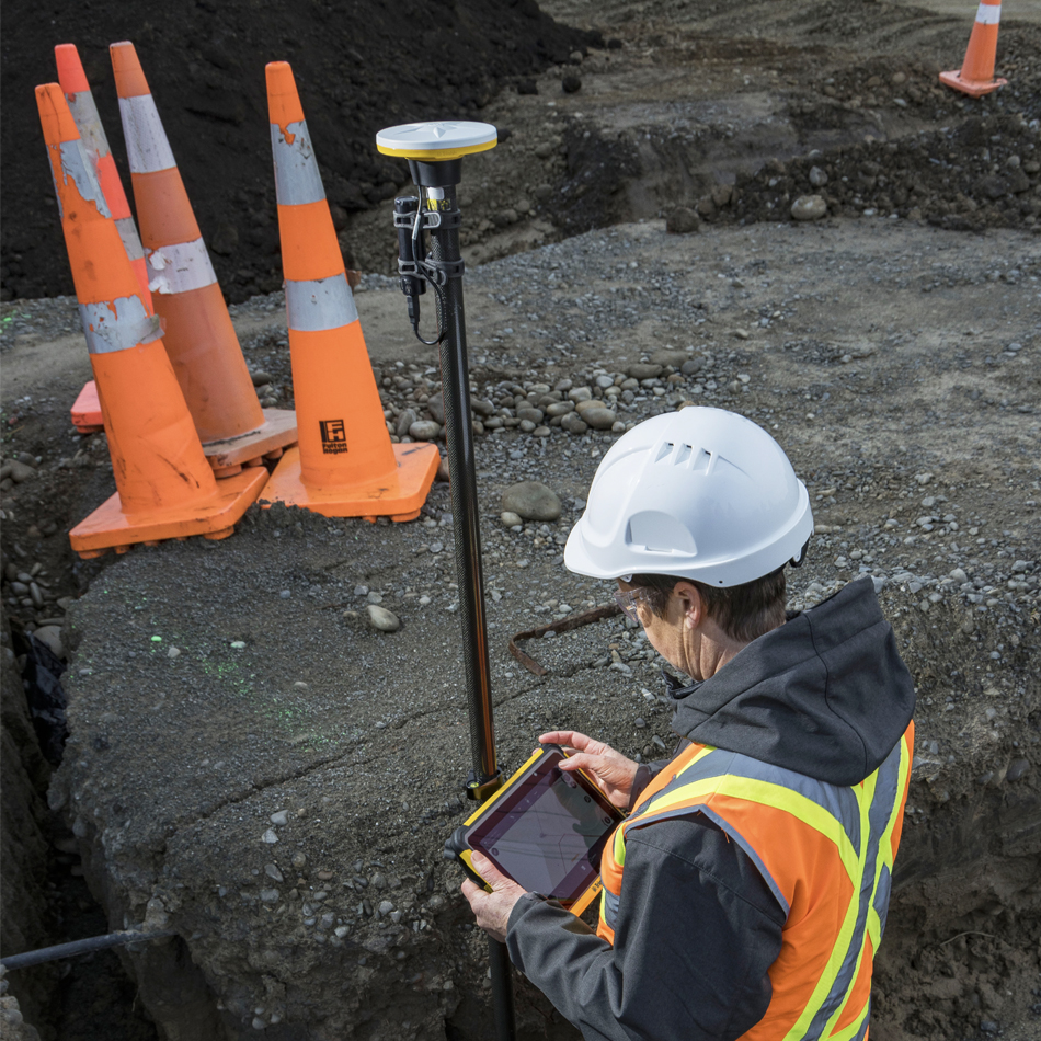Topógrafo con chaleco de alta visibilidad utilizando Trimble Catalyst con un receptor DA2